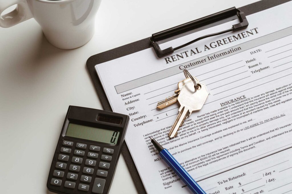 lease-management keys, a pen, and calculator sit on top of a rental agreement document