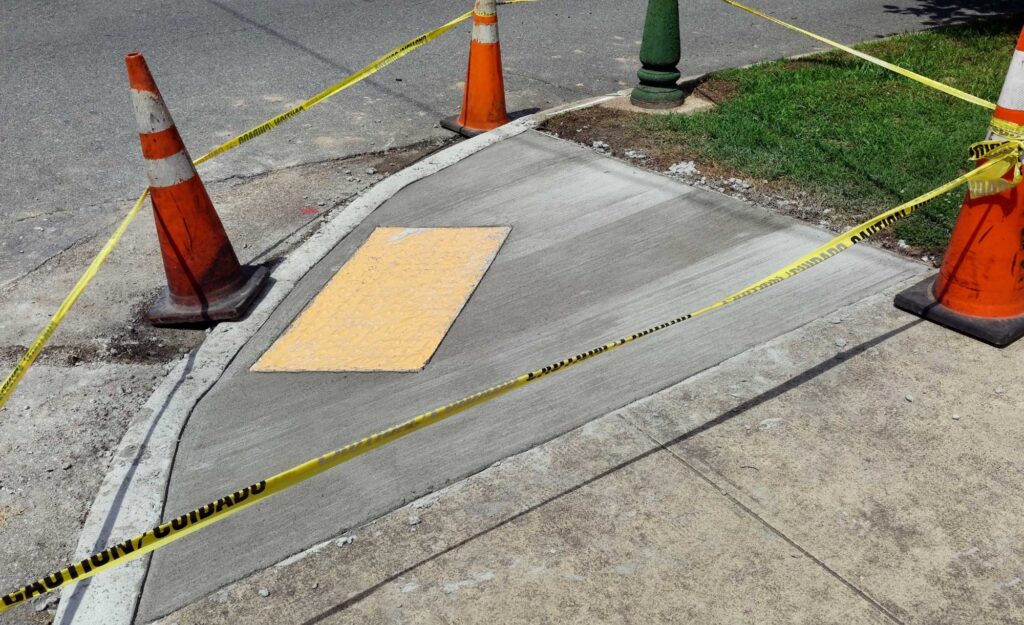 responsive-service-new caution tape tied around cones outlining freshly poured concrete sidewalk